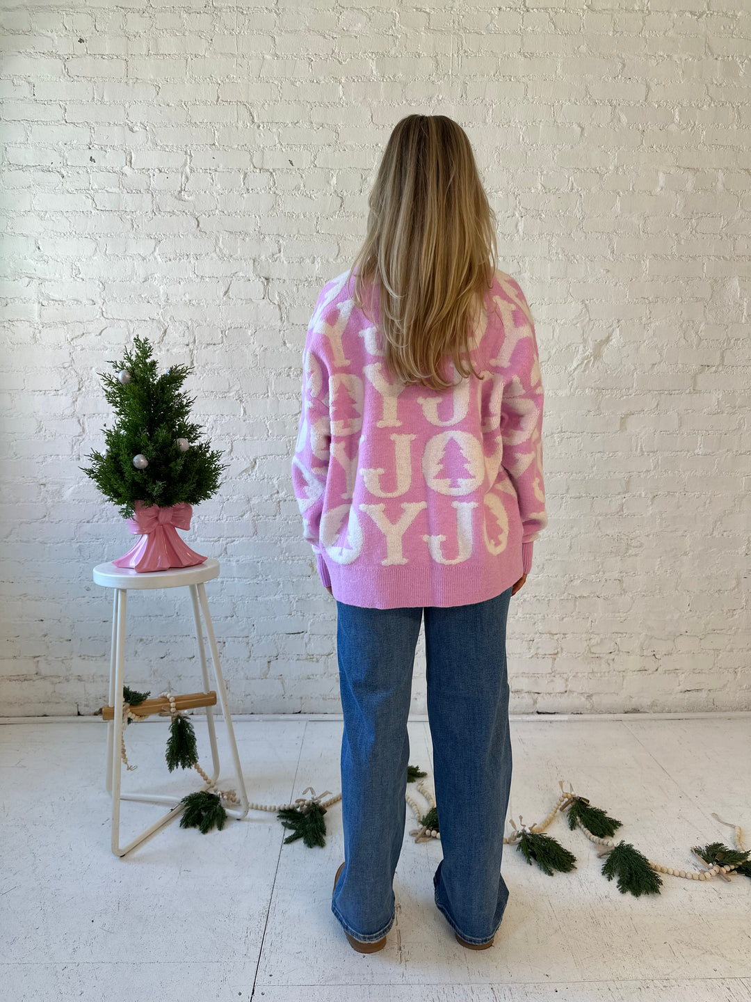 Woman wearing lilac purple oversized crewneck sweater with "Joy" written all over. 