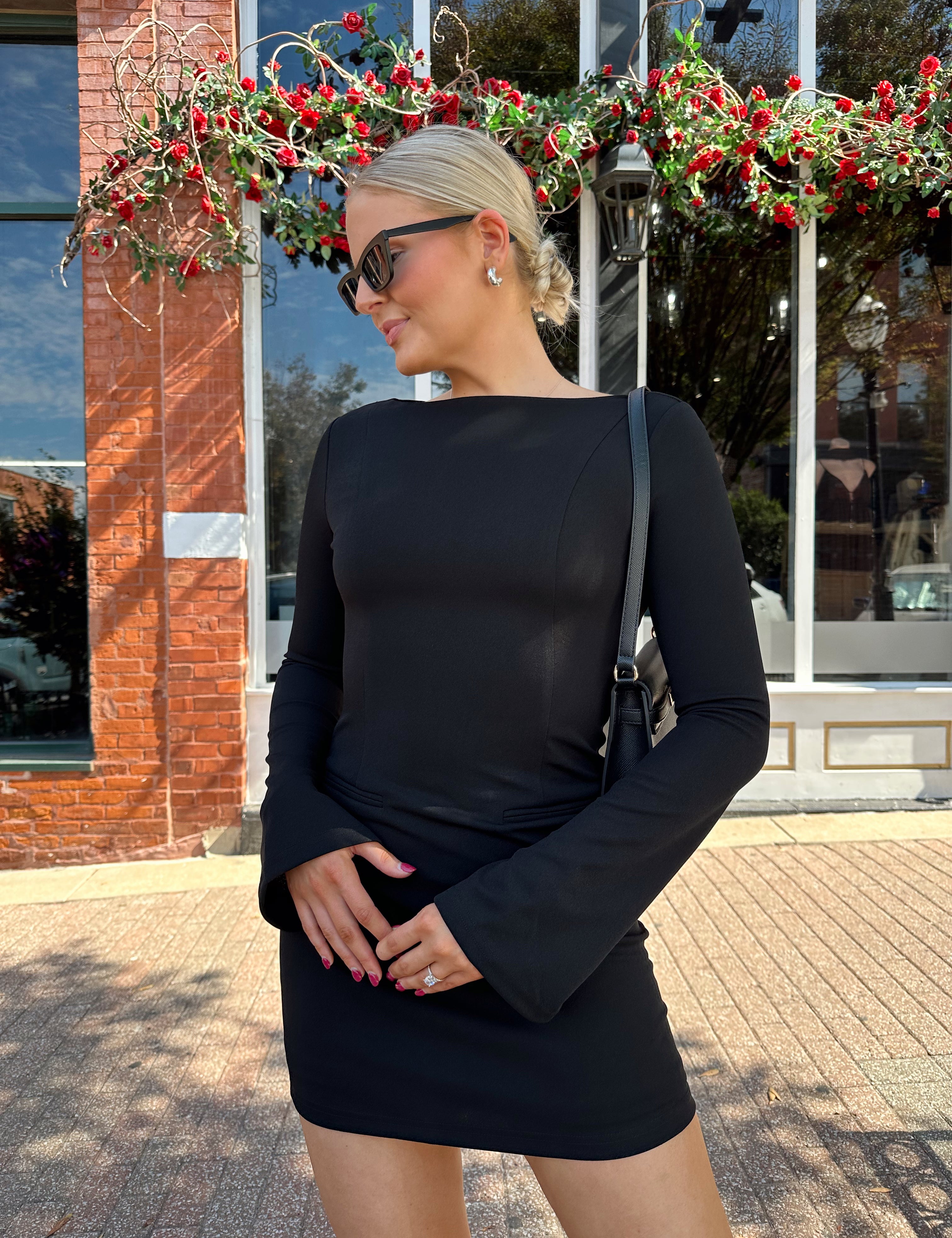 Woman wearing black long sleeve mini dress with black heels. 