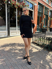 Woman wearing black long sleeve mini dress with black heels. 