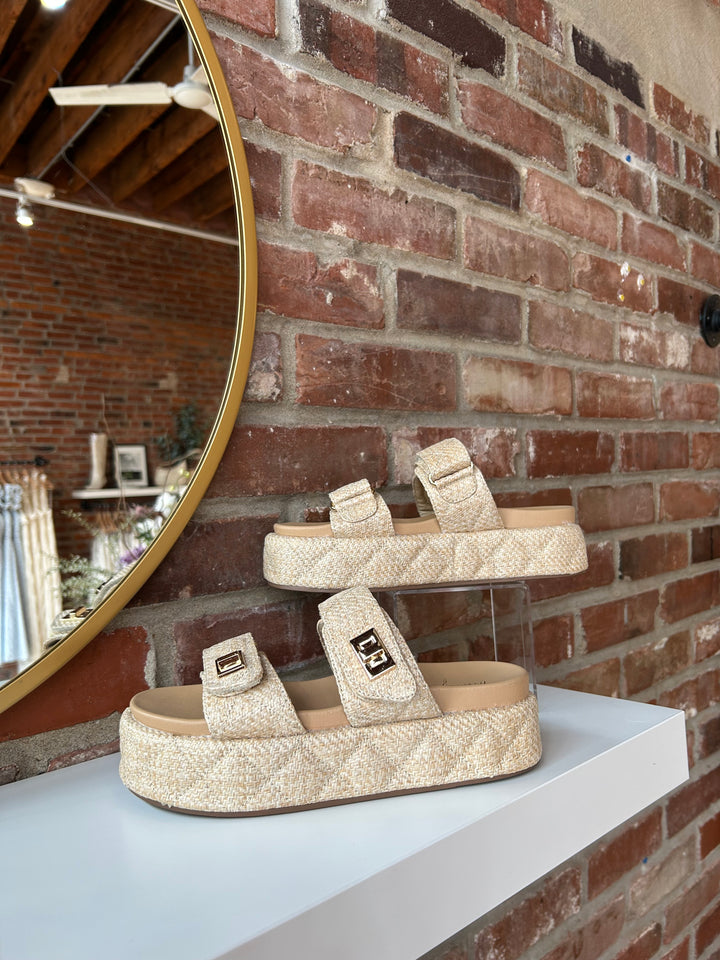 Quilted platform slide on sandals with gold hardware detailing.