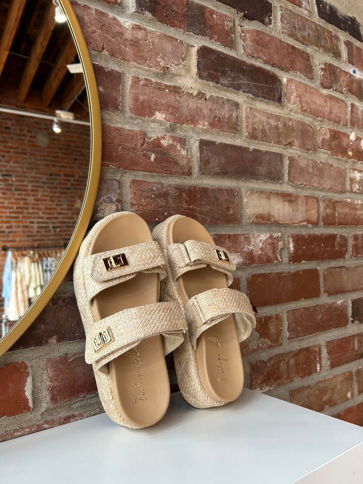 Quilted platform slide on sandals with gold hardware detailing.