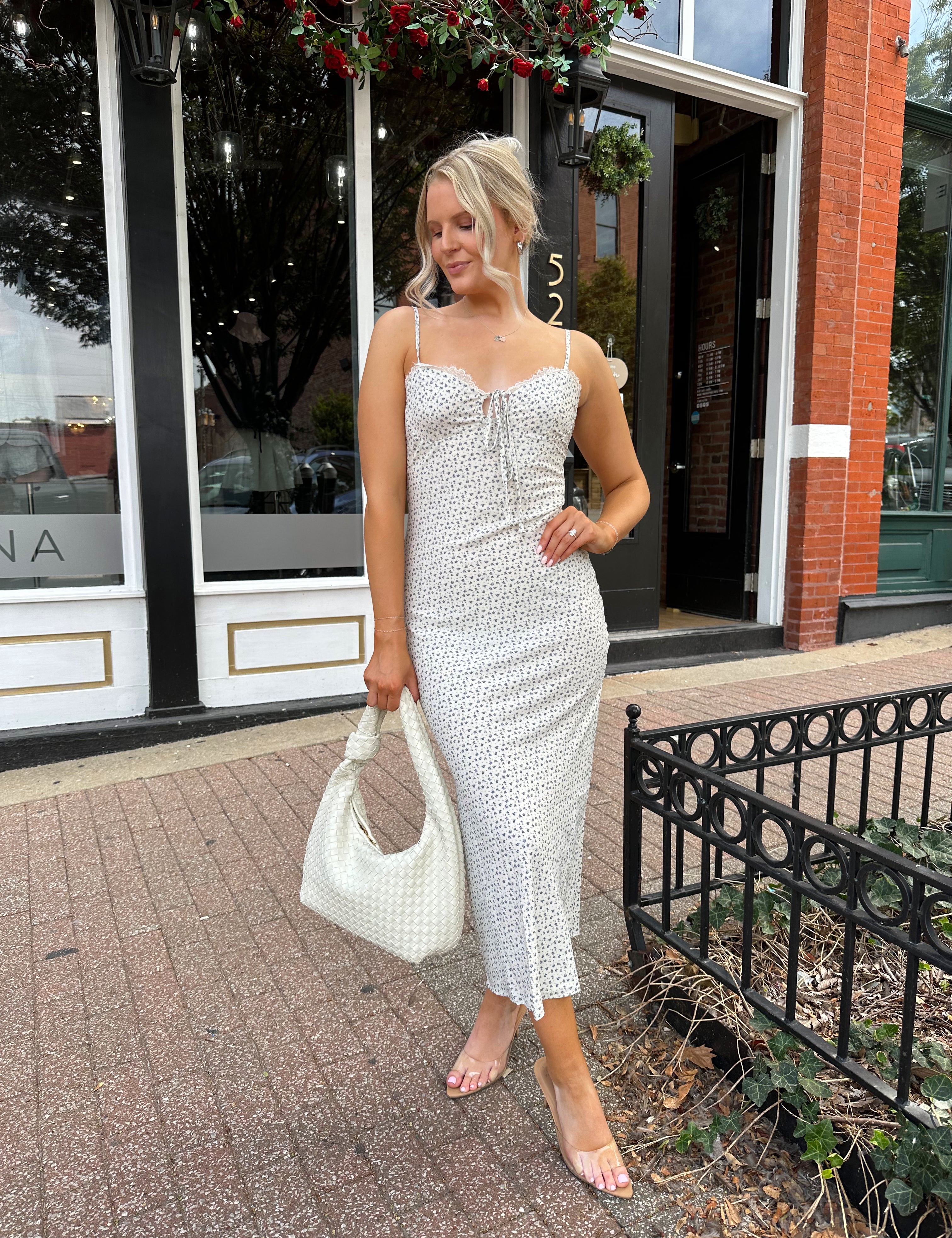 Woman wearing cream midi dress with blue floral pattern with lace trim detail. 