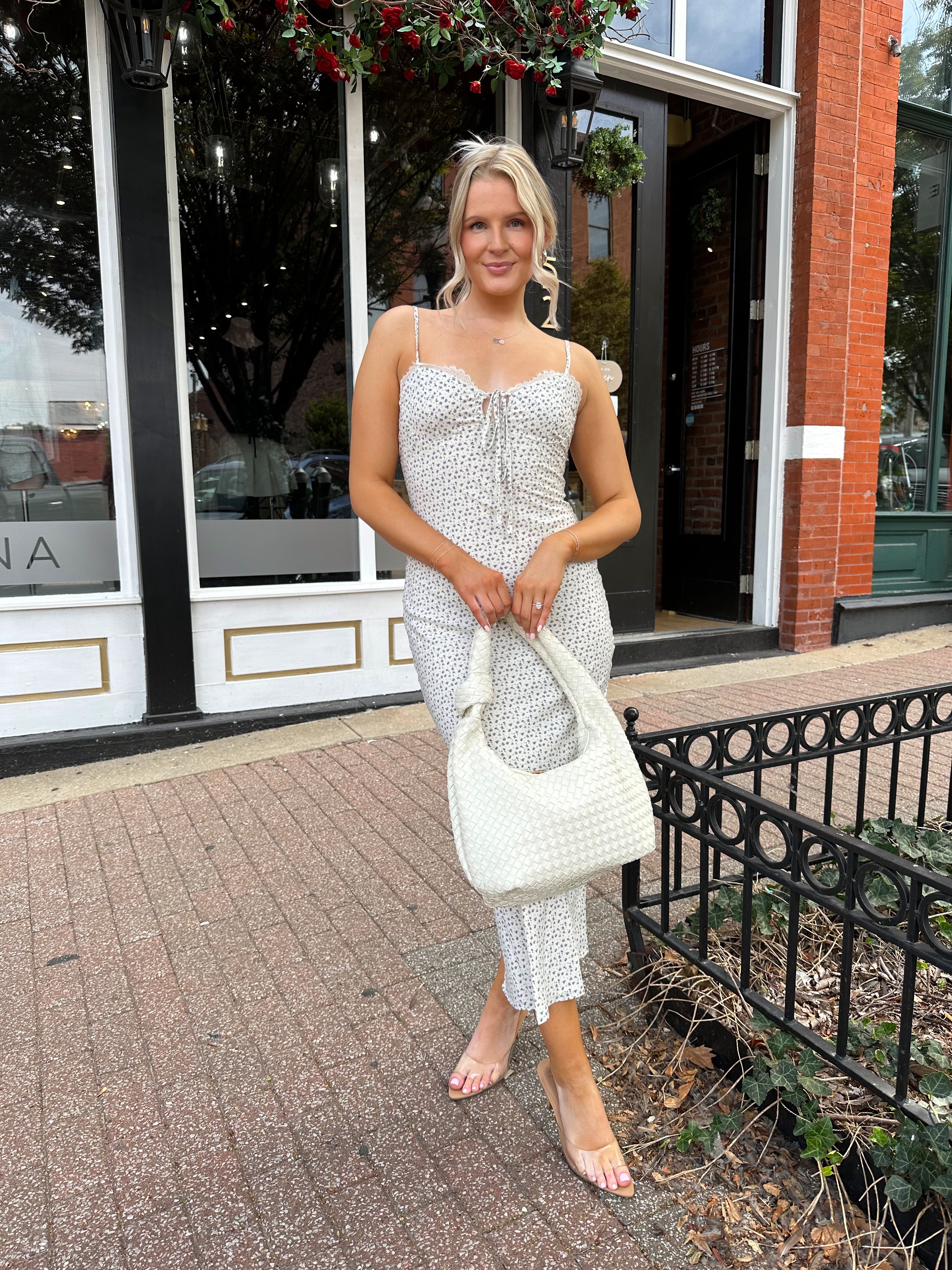 Woman wearing cream midi dress with blue floral pattern with lace trim detail. 