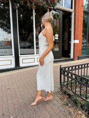 Woman wearing cream midi dress with blue floral pattern with lace trim detail. 