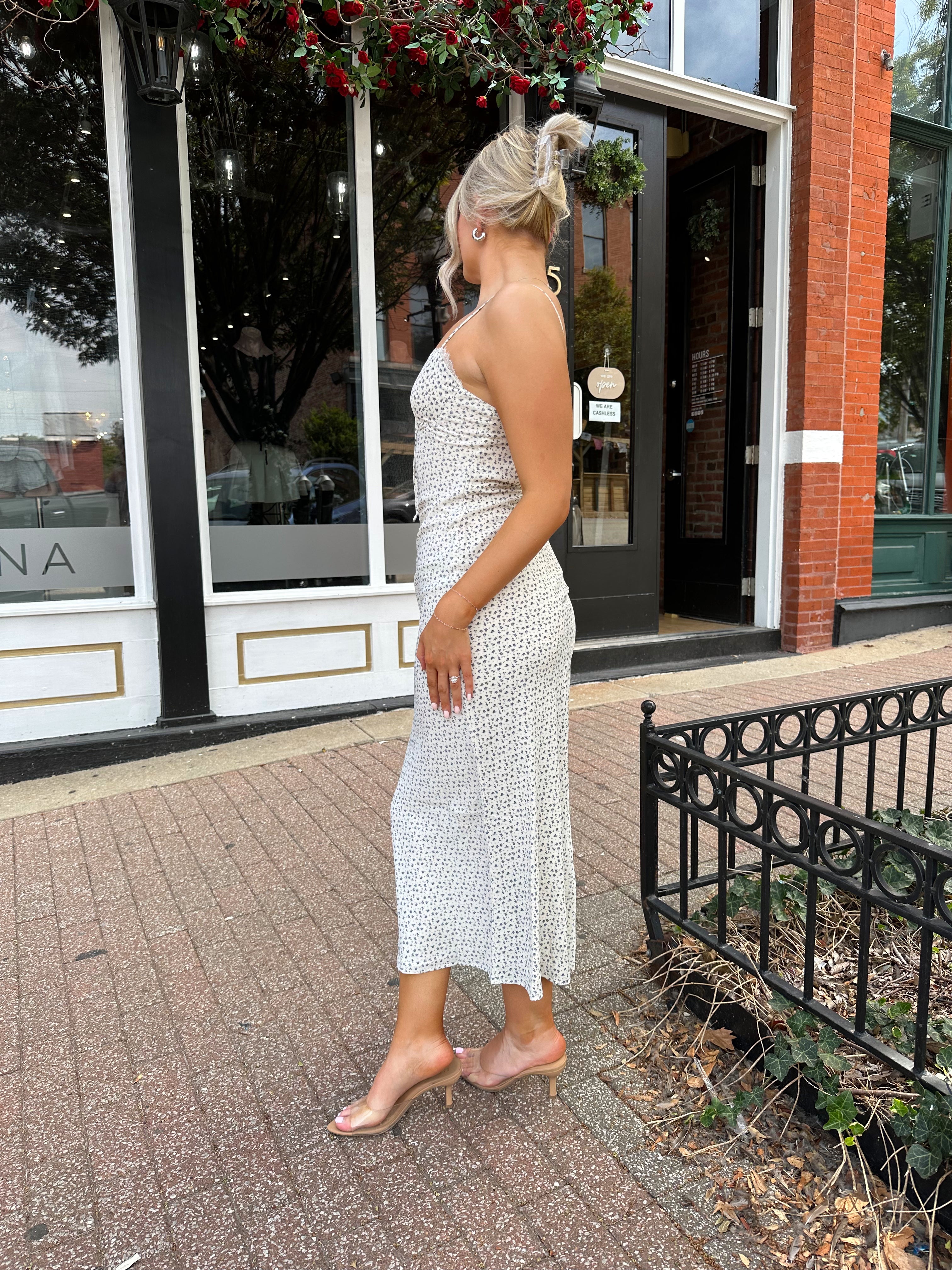 Woman wearing cream midi dress with blue floral pattern with lace trim detail. 
