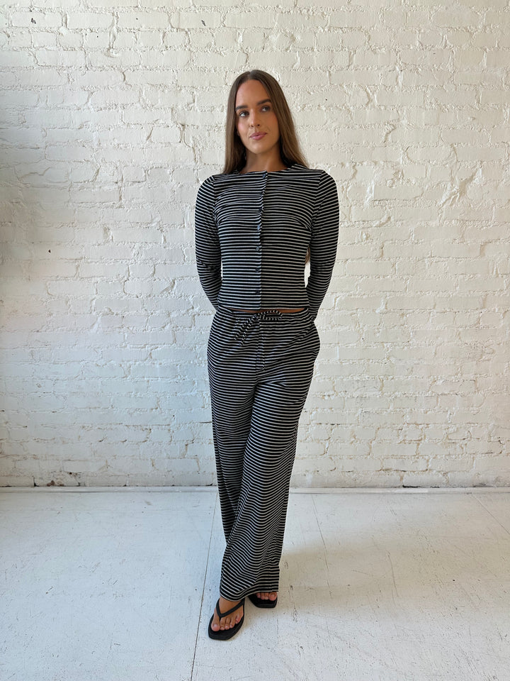 Woman wearing black striped two piece lounge set with button down long sleeve top.