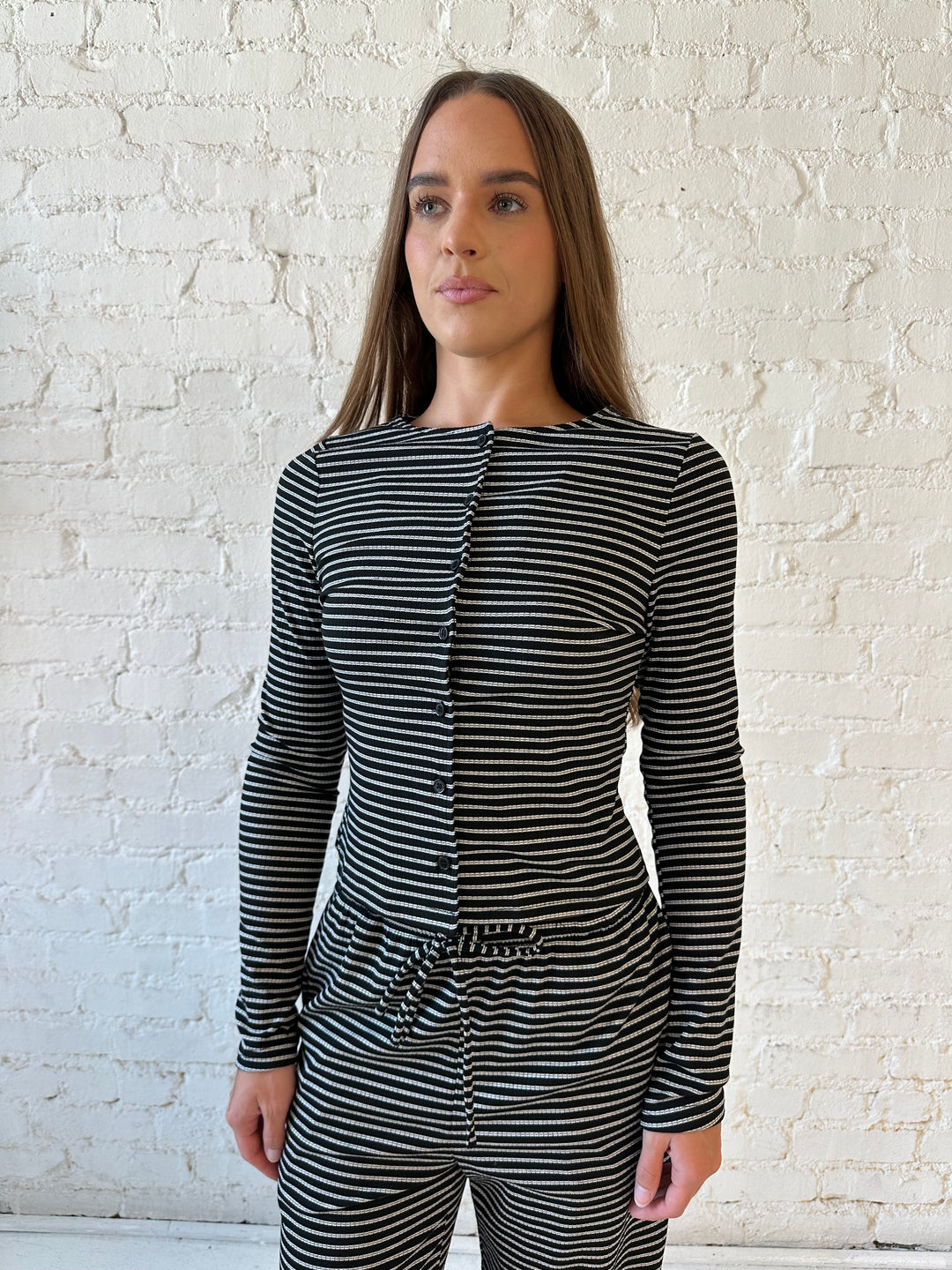 Woman wearing black striped two piece lounge set with button down long sleeve top.