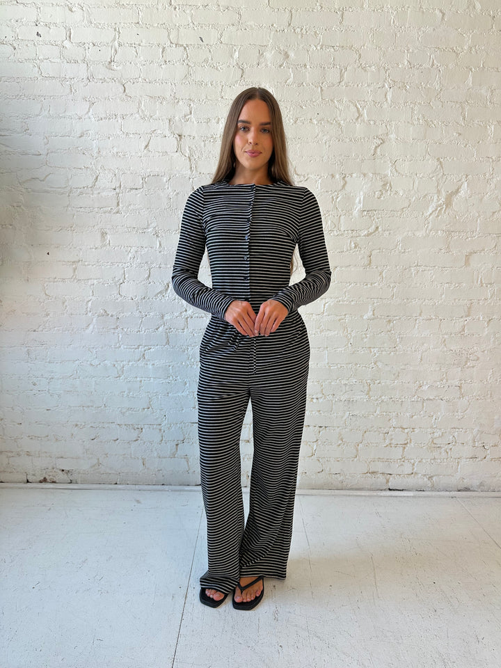 Woman wearing black striped two piece lounge set with button down long sleeve top.