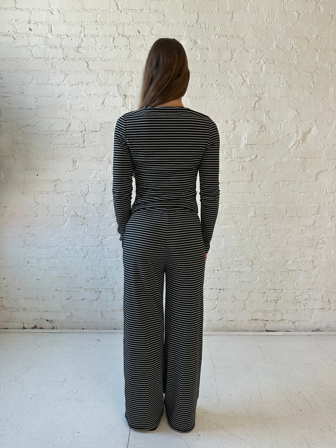 Woman wearing black striped two piece lounge set with button down long sleeve top.