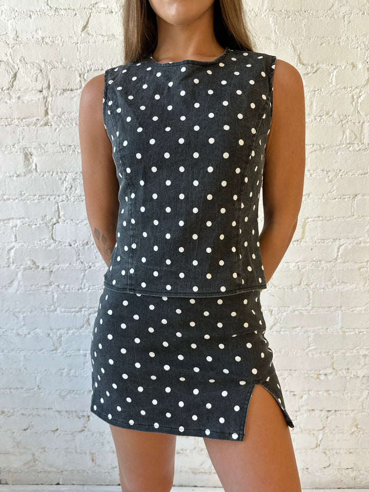 Woman wearing charcoal grey polka dot denim set with open tie back, and high waisted mini skort. 