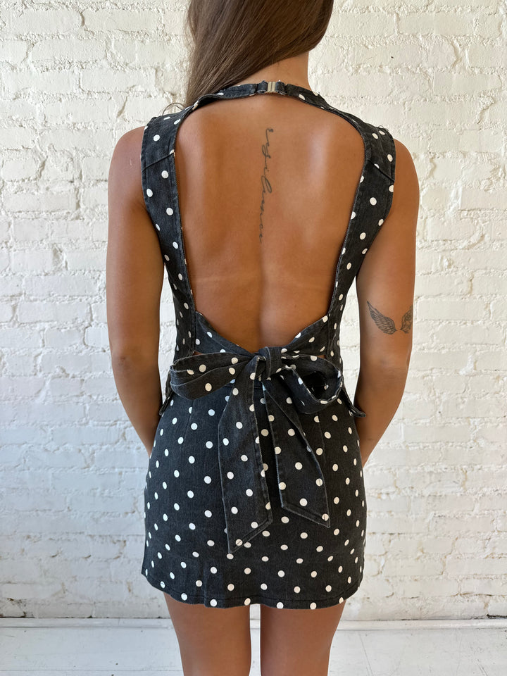 Woman wearing charcoal grey polka dot denim set with open tie back, and high waisted mini skort. 