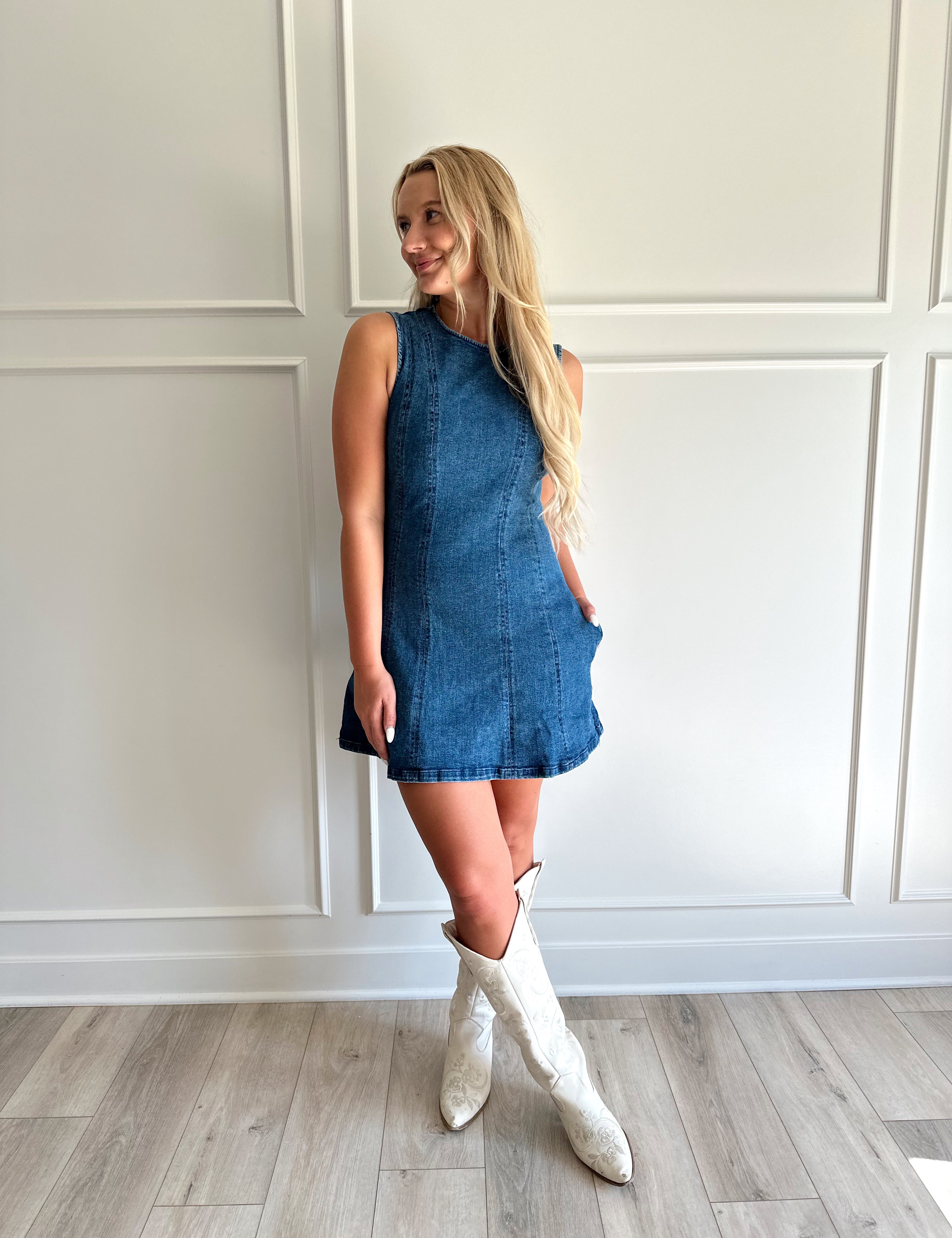 Woman wearing a dark wash denim mini dress with functional pockets.