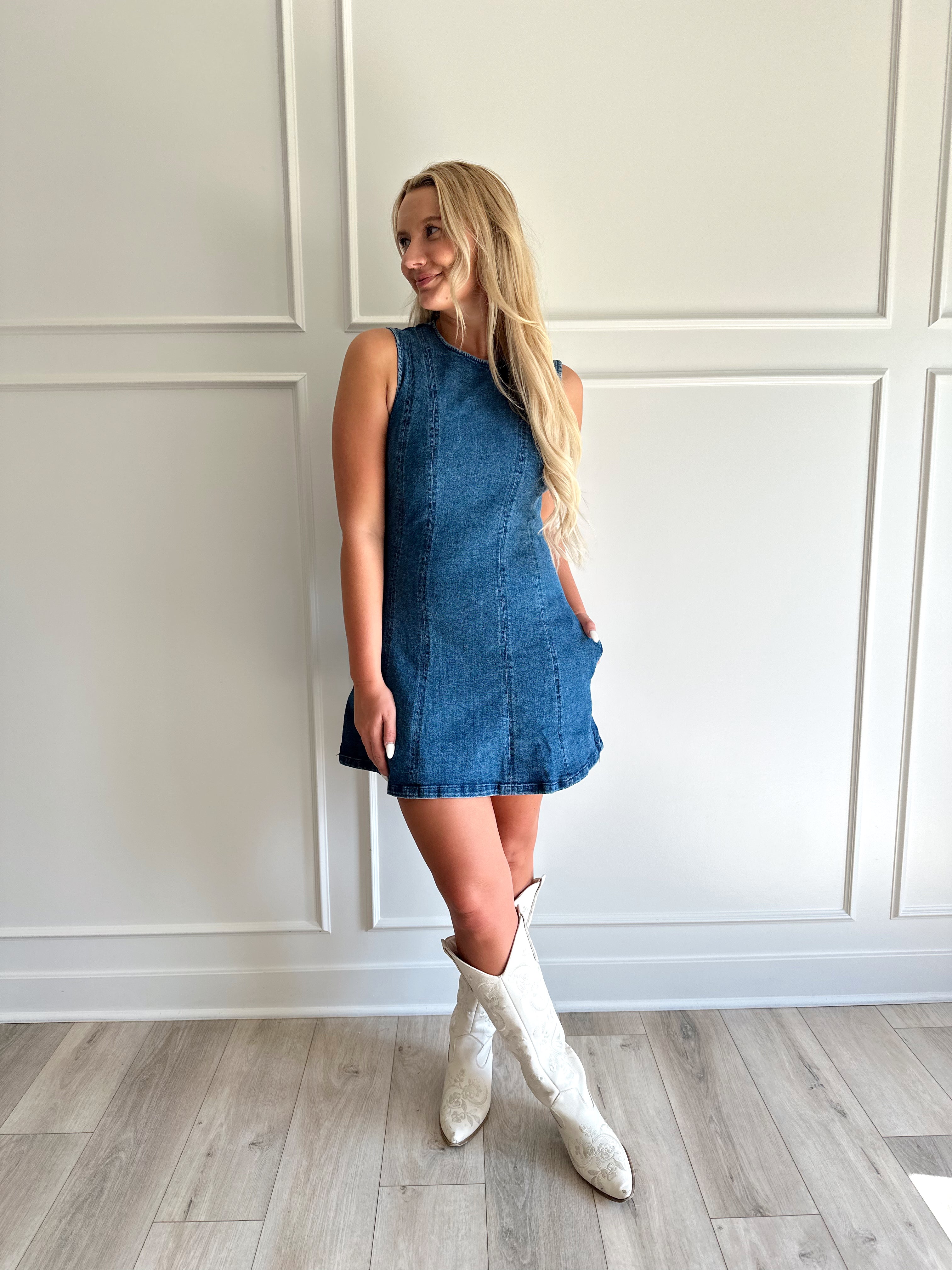Woman wearing a dark wash denim mini dress with functional pockets.