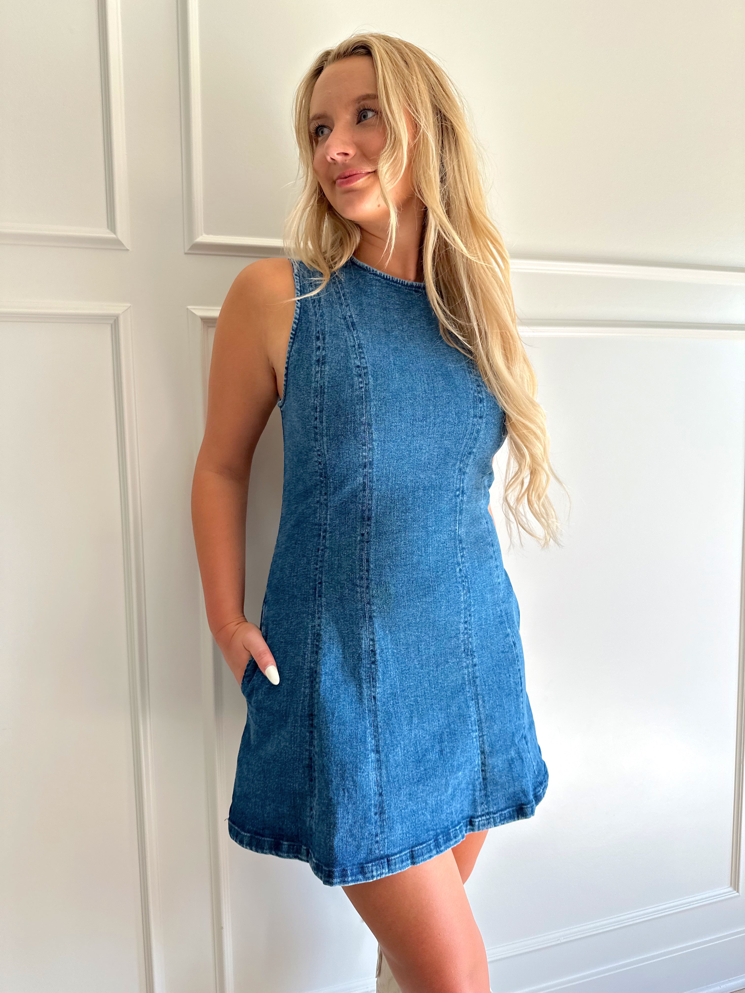Woman wearing a dark wash denim mini dress with functional pockets.
