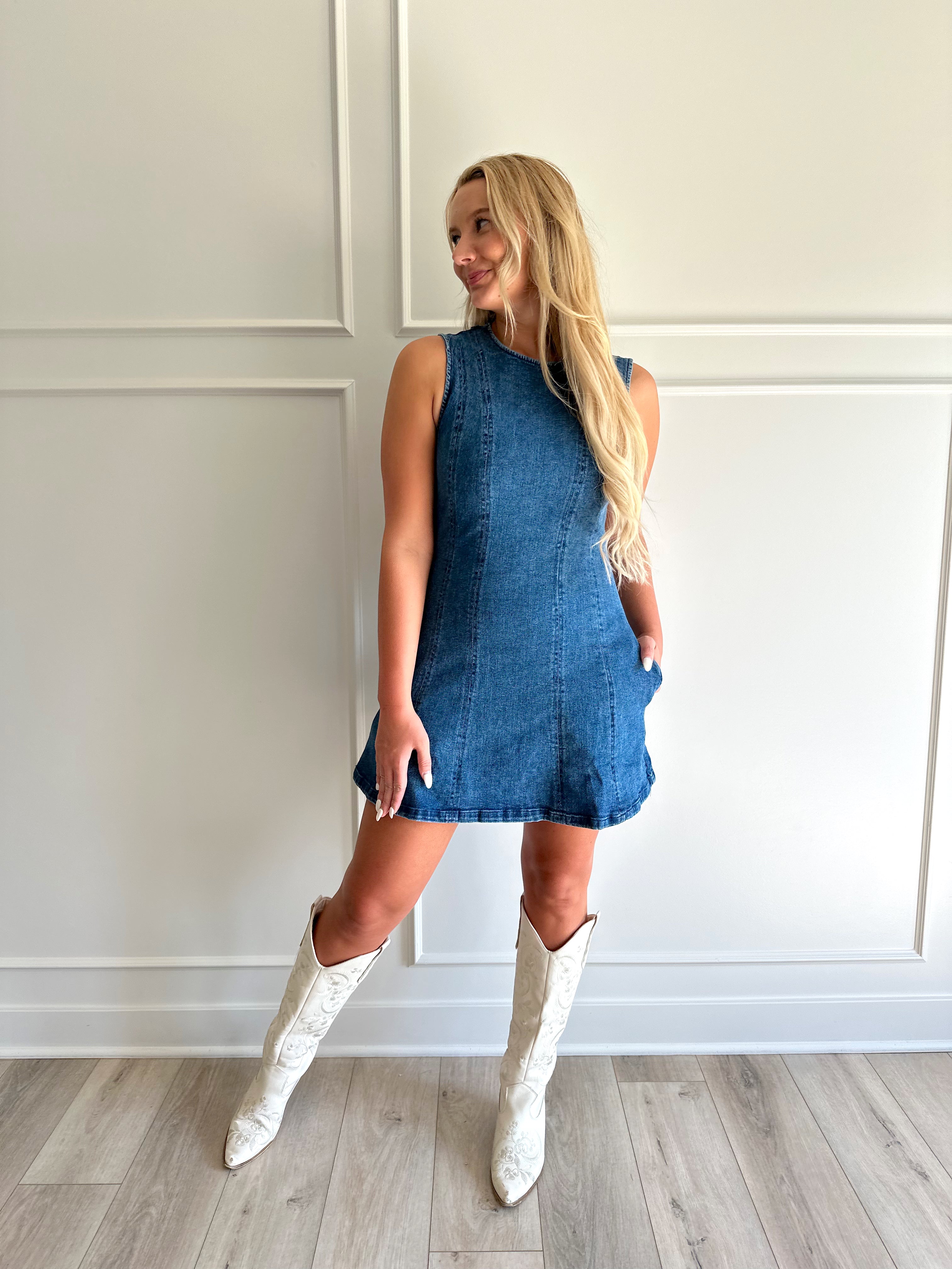 Woman wearing a dark wash denim mini dress with functional pockets.