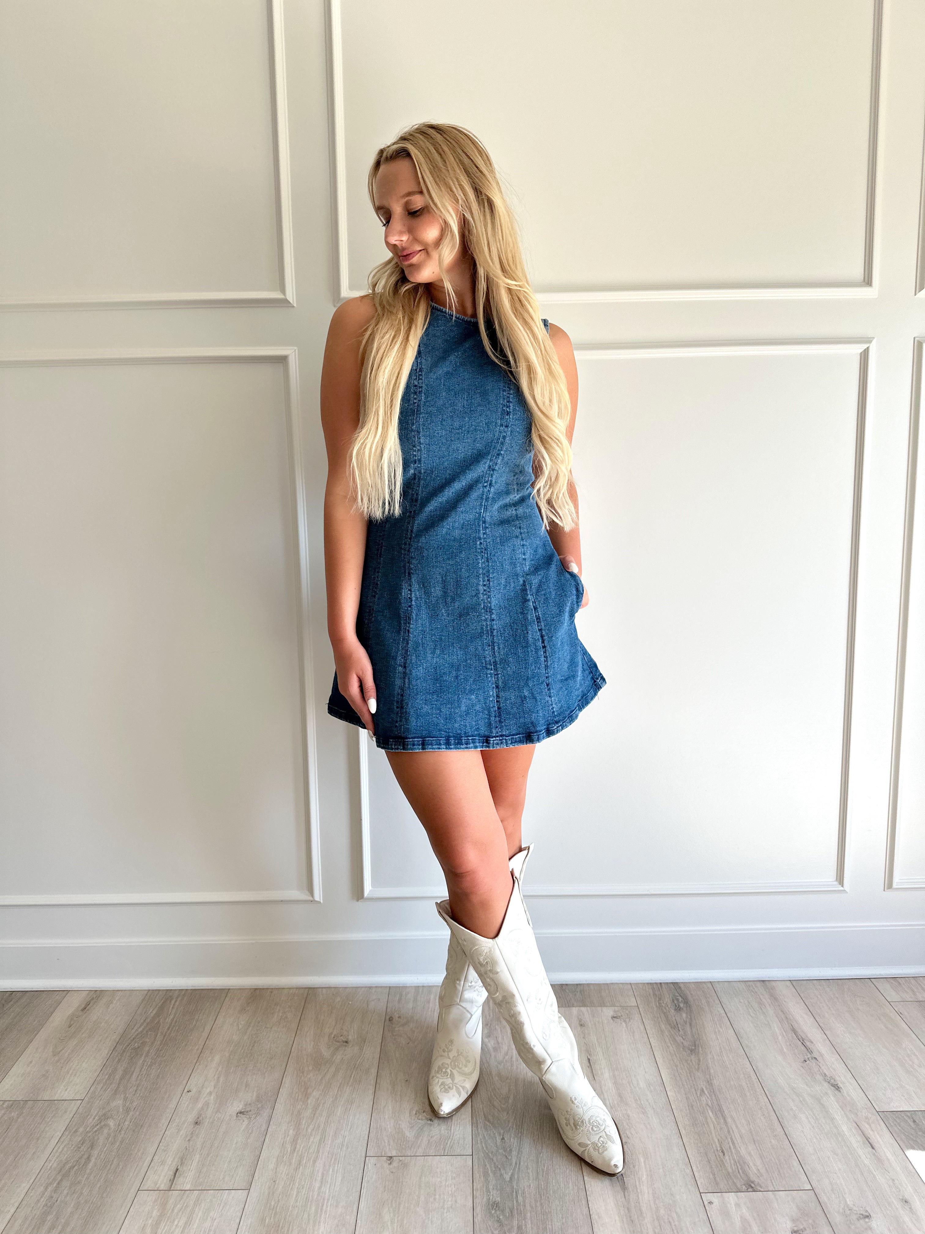 Woman wearing a dark wash denim mini dress with functional pockets.