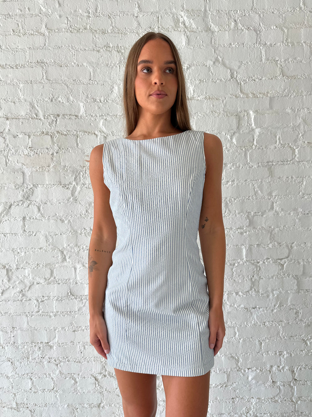 Woman wearing blue striped mini dress with deep low back.