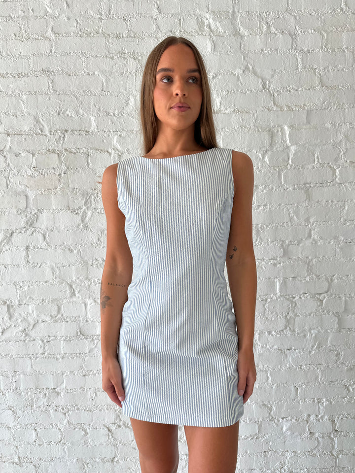 Woman wearing blue striped mini dress with deep low back.