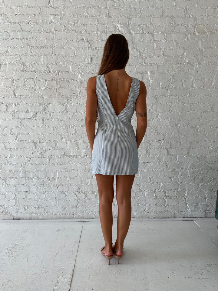 Woman wearing blue striped mini dress with deep low back.