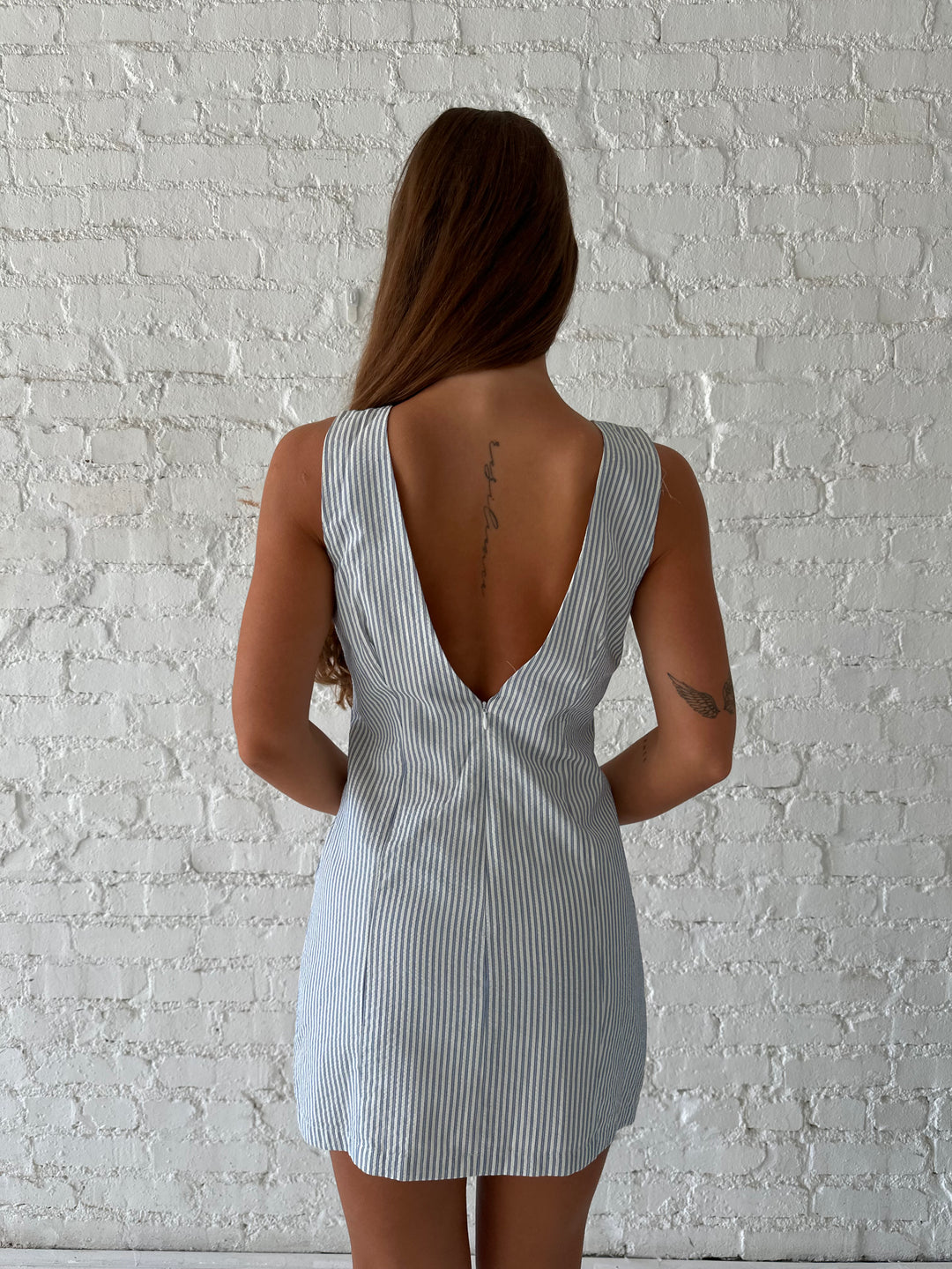 Woman wearing blue striped mini dress with deep low back.