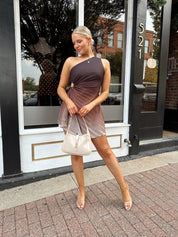 Woman wearing one shoulder brown ombré pleated mini dress with adjustable side cutout. 