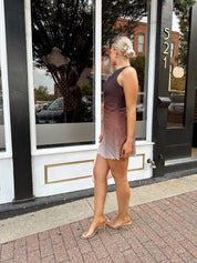 Woman wearing one shoulder brown ombré pleated mini dress with adjustable side cutout. 