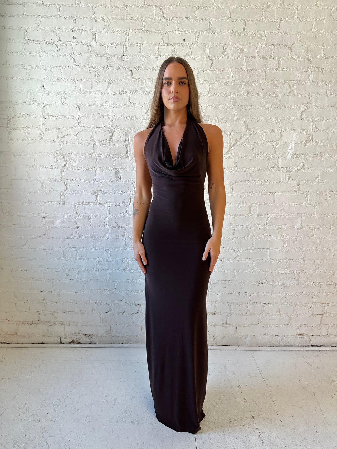 Woman wearing brown cowl neck maxi dress with open back and support strap.