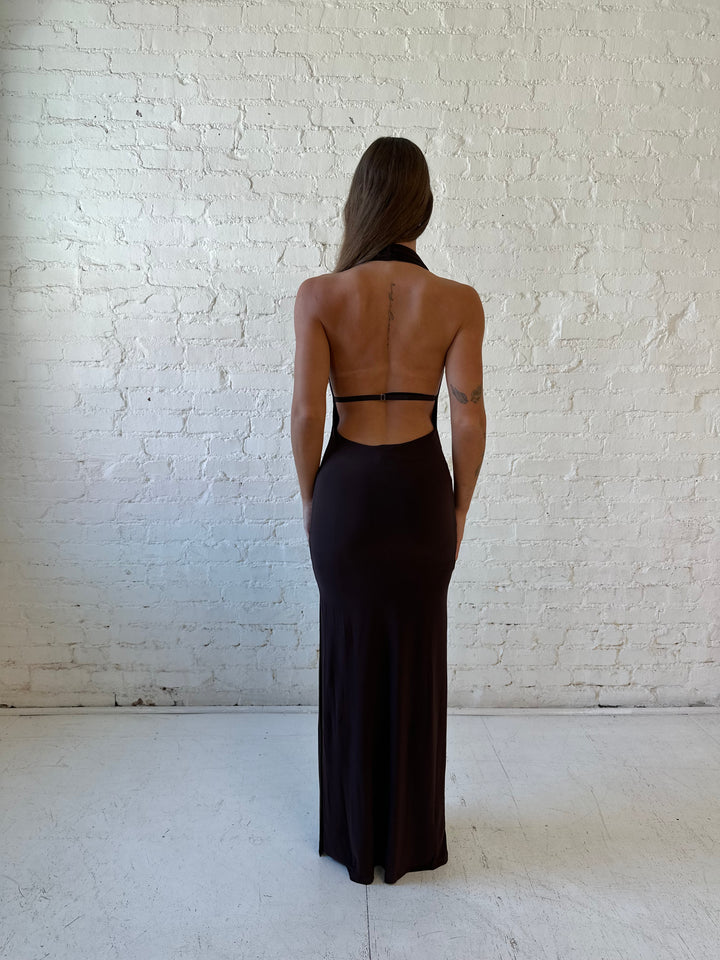 Woman wearing brown cowl neck maxi dress with open back and support strap.