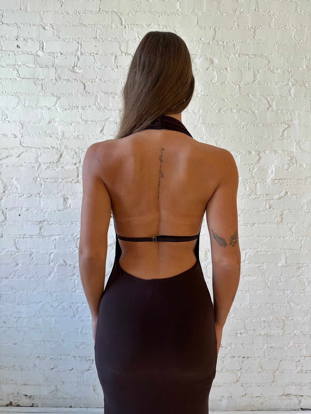 Woman wearing brown cowl neck maxi dress with open back and support strap.