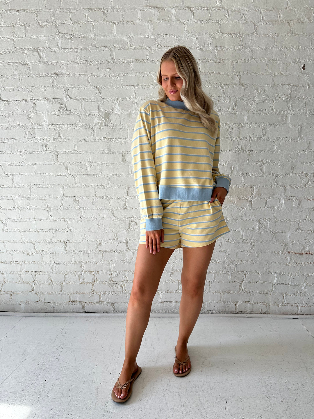 Woman wearing yellow striped two piece lounge set.