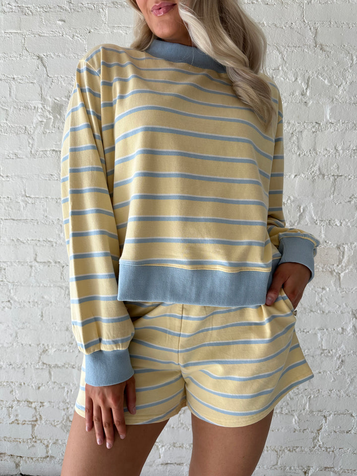 Woman wearing yellow striped two piece lounge set.