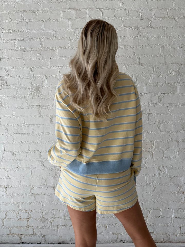 Woman wearing yellow striped two piece lounge set.