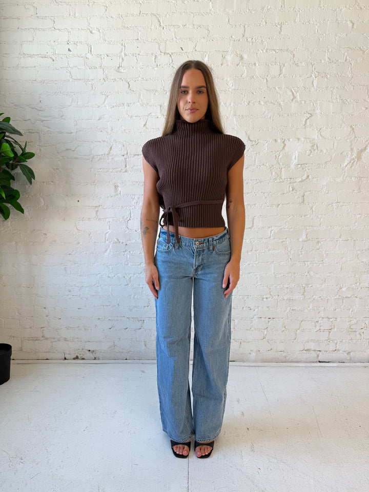 Woman wearing green knit short sleeve top with self tie waist detail.