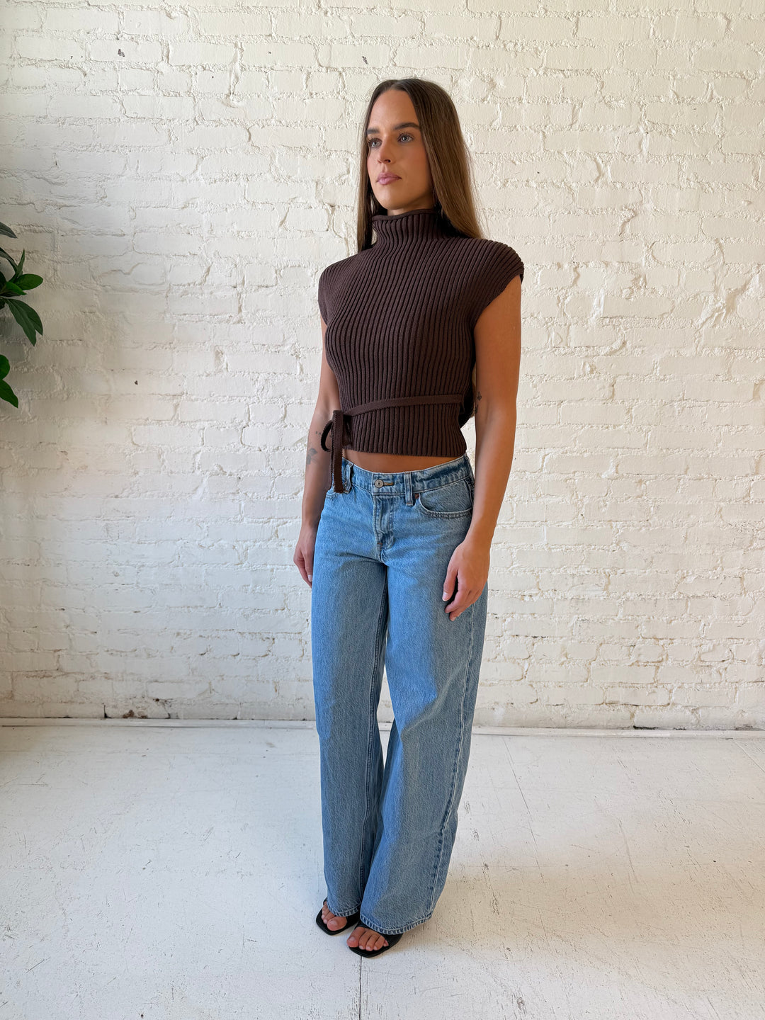 Woman wearing green knit short sleeve top with self tie waist detail.