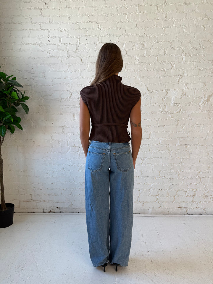Woman wearing green knit short sleeve top with self tie waist detail.