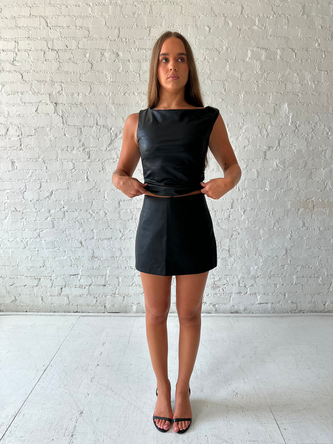 Woman wearing black leather mini skort with black leather top.