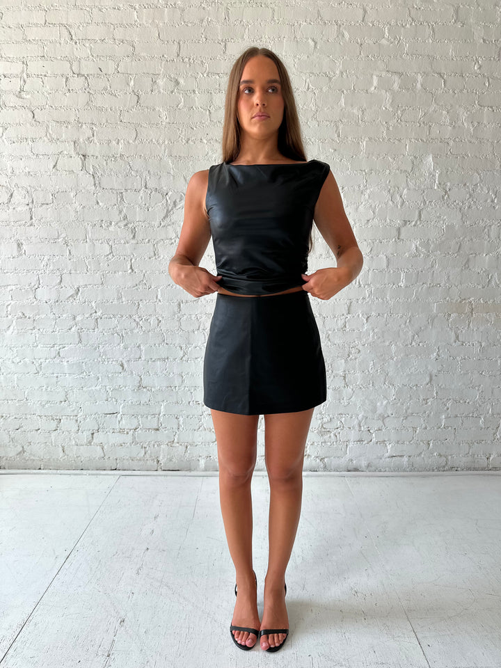 Woman wearing black leather mini skort with black leather top.