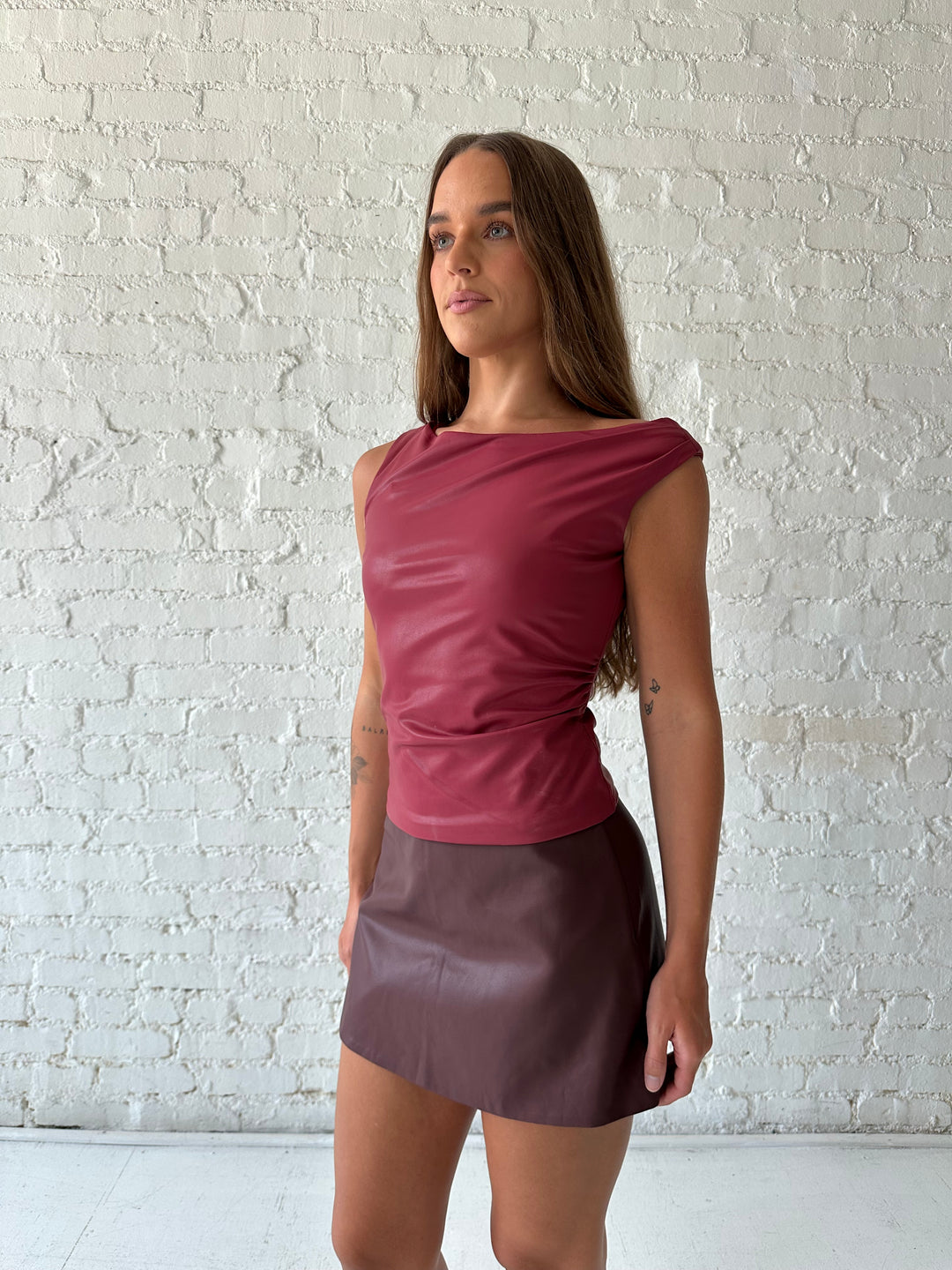 Woman wearing burgundy leather mini skort with red leather top.