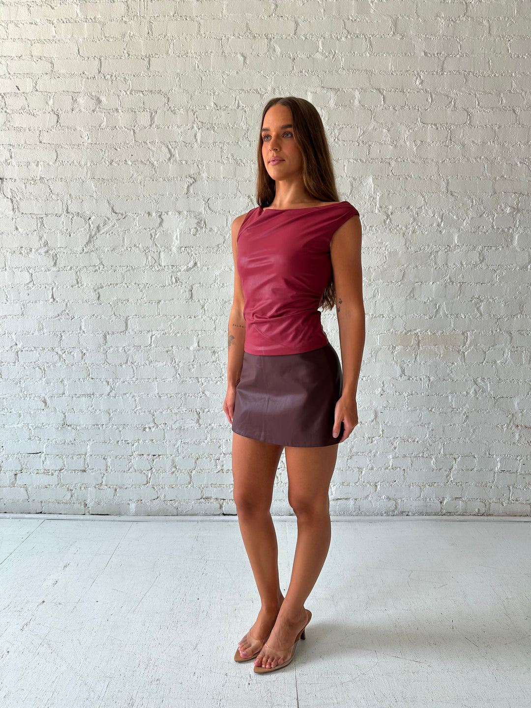 Woman wearing burgundy leather mini skort with red leather top.