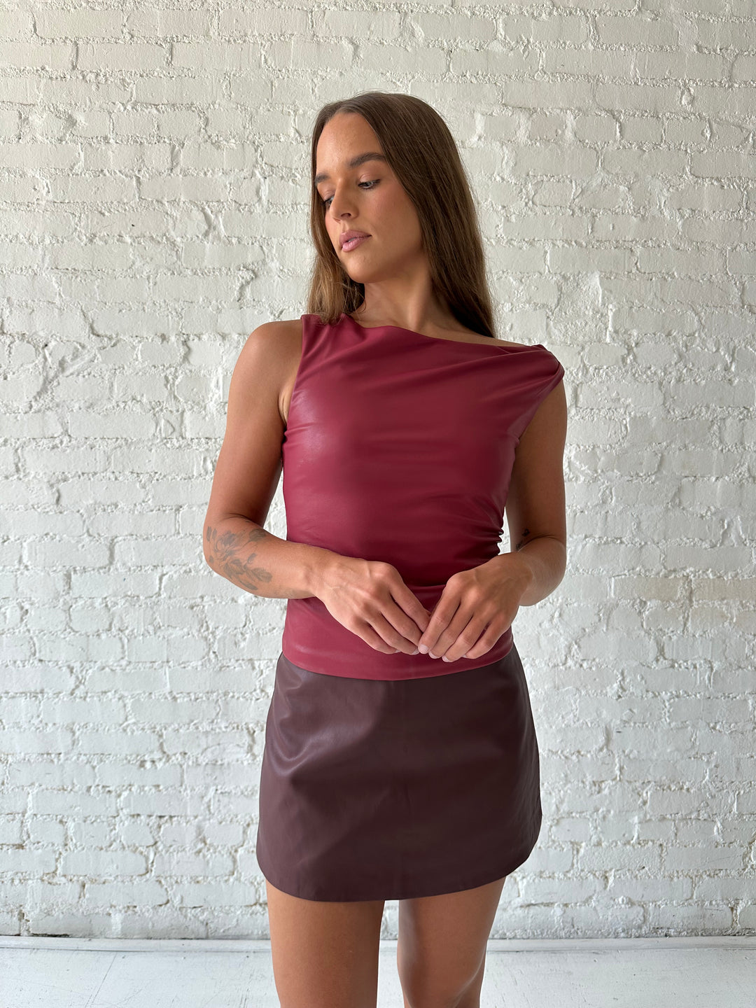 Woman wearing burgundy leather mini skort with red leather top.