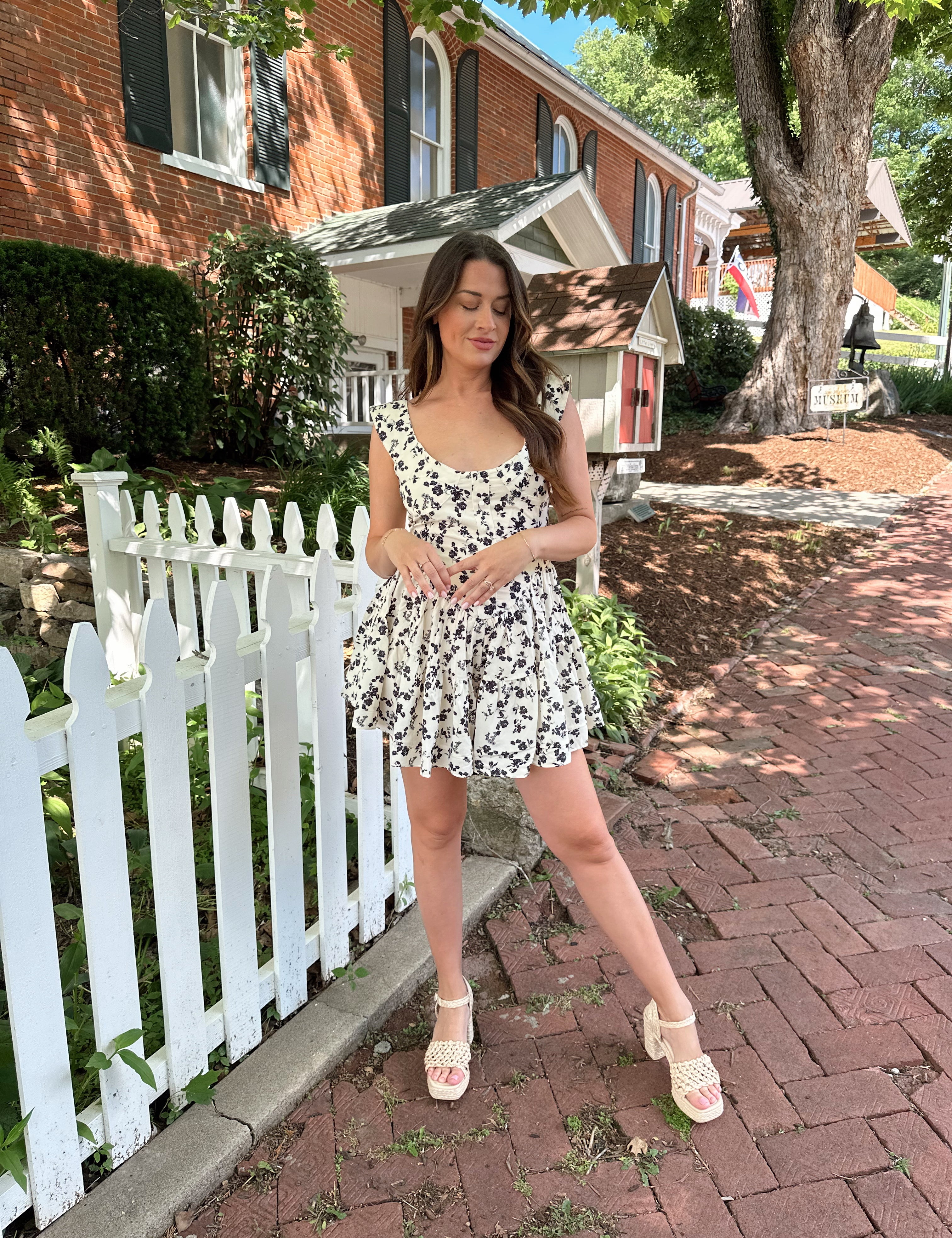 Ivory tiered romper with black floral pattern and button detailing.