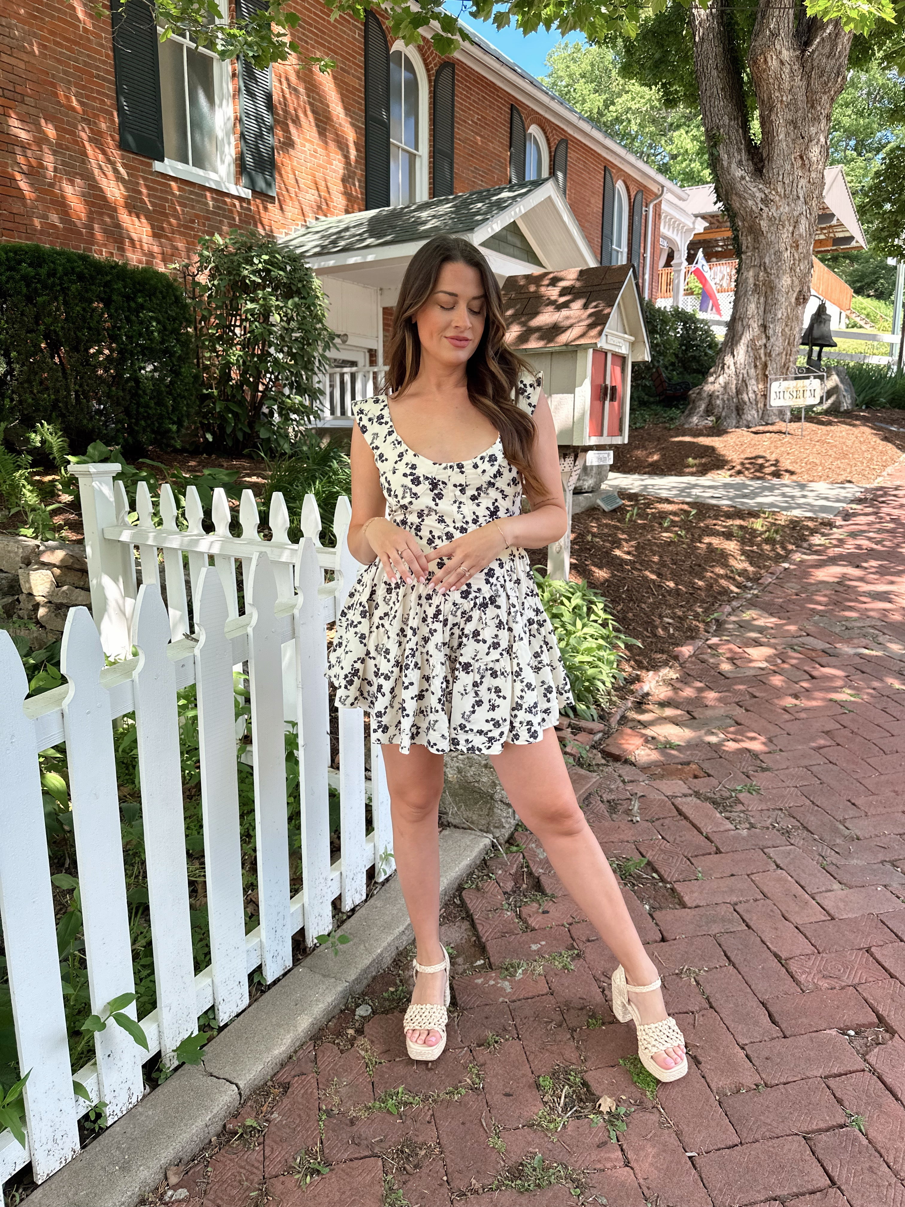 Ivory tiered romper with black floral pattern and button detailing.