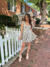 Ivory tiered romper with black floral pattern and button detailing.