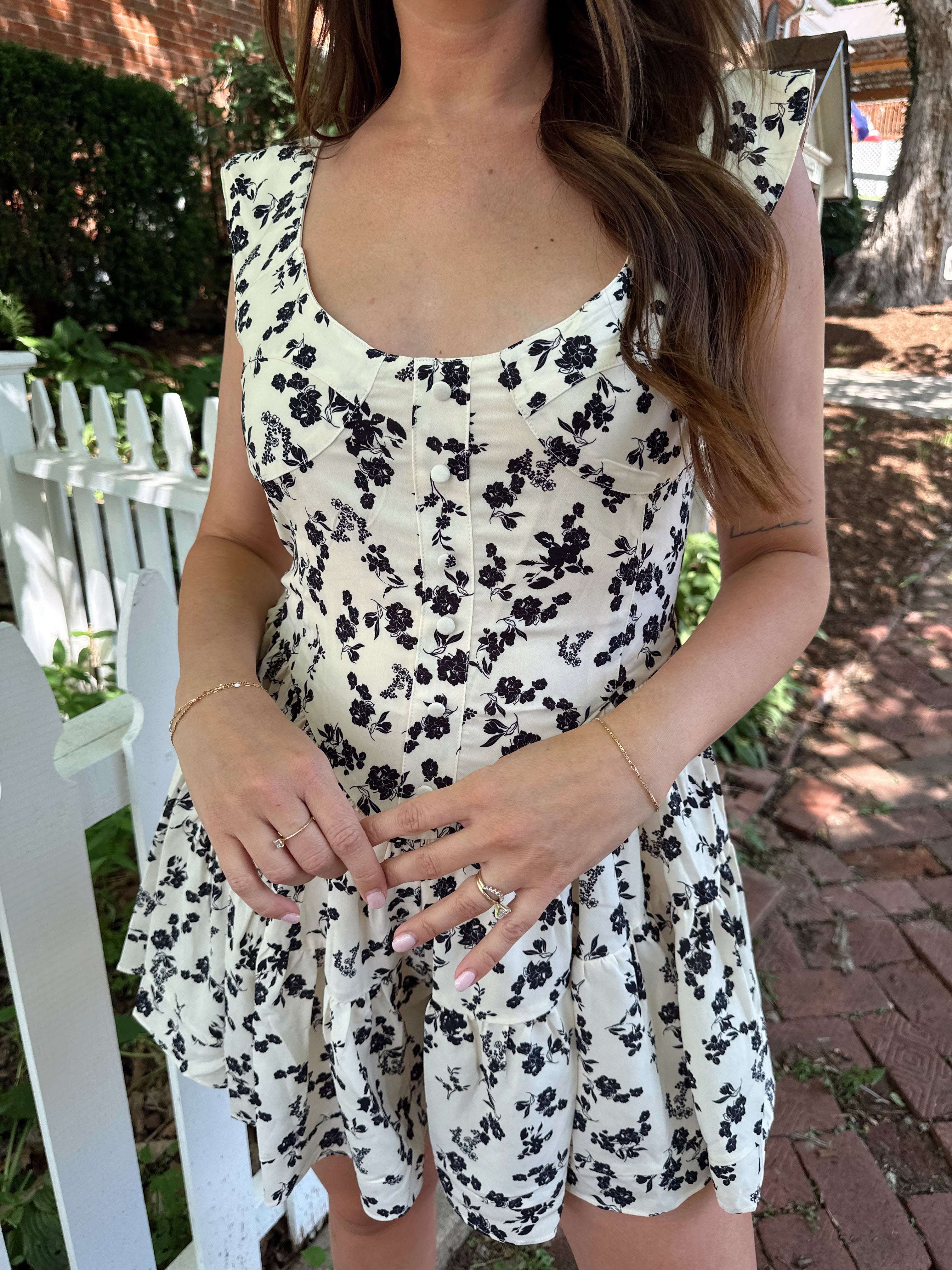 Ivory tiered romper with black floral pattern and button detailing.