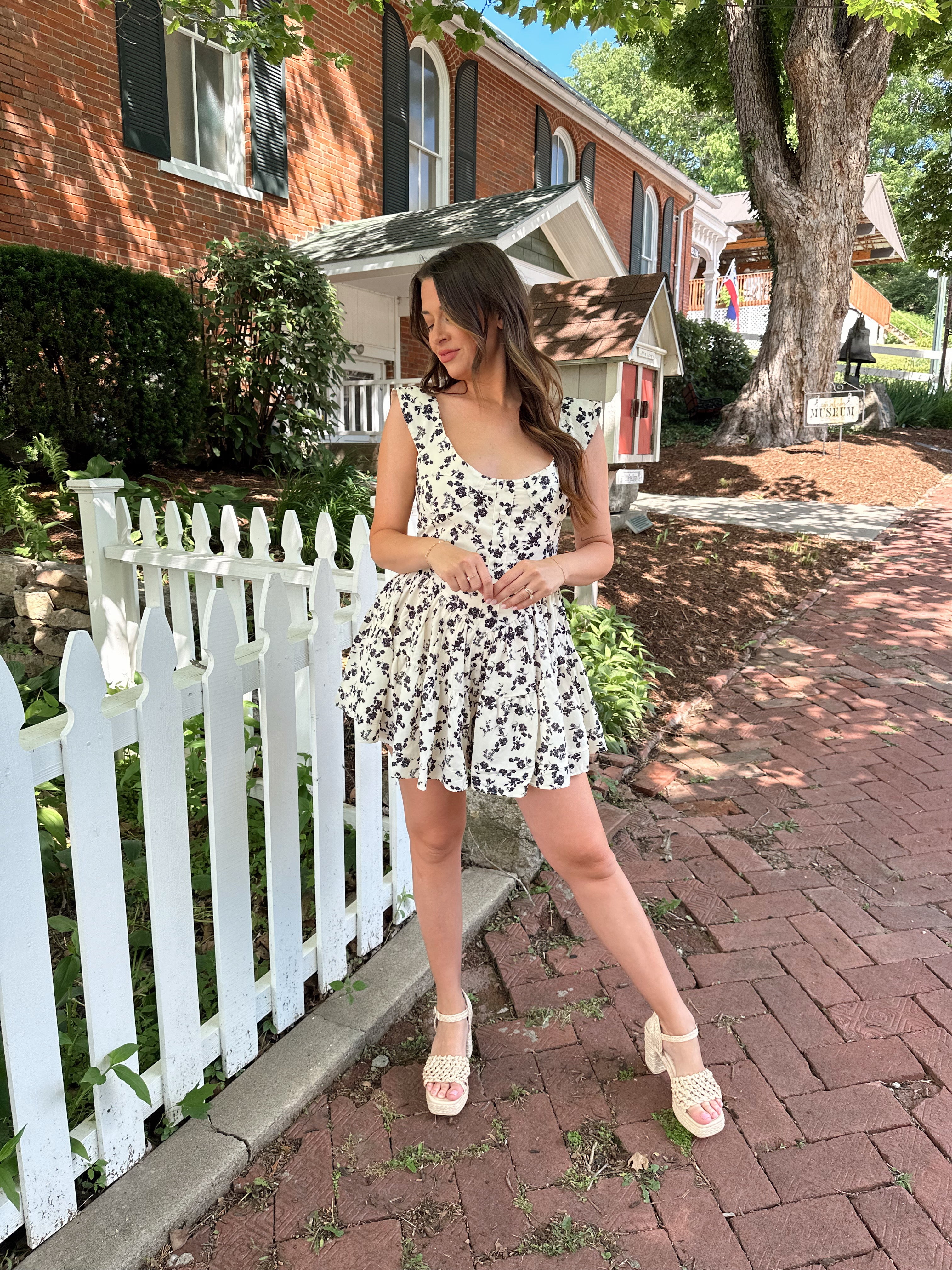 Ivory tiered romper with black floral pattern and button detailing.