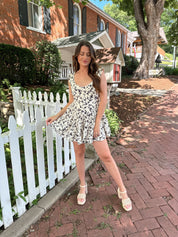 Ivory tiered romper with black floral pattern and button detailing.