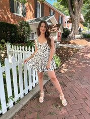 Ivory tiered romper with black floral pattern and button detailing.