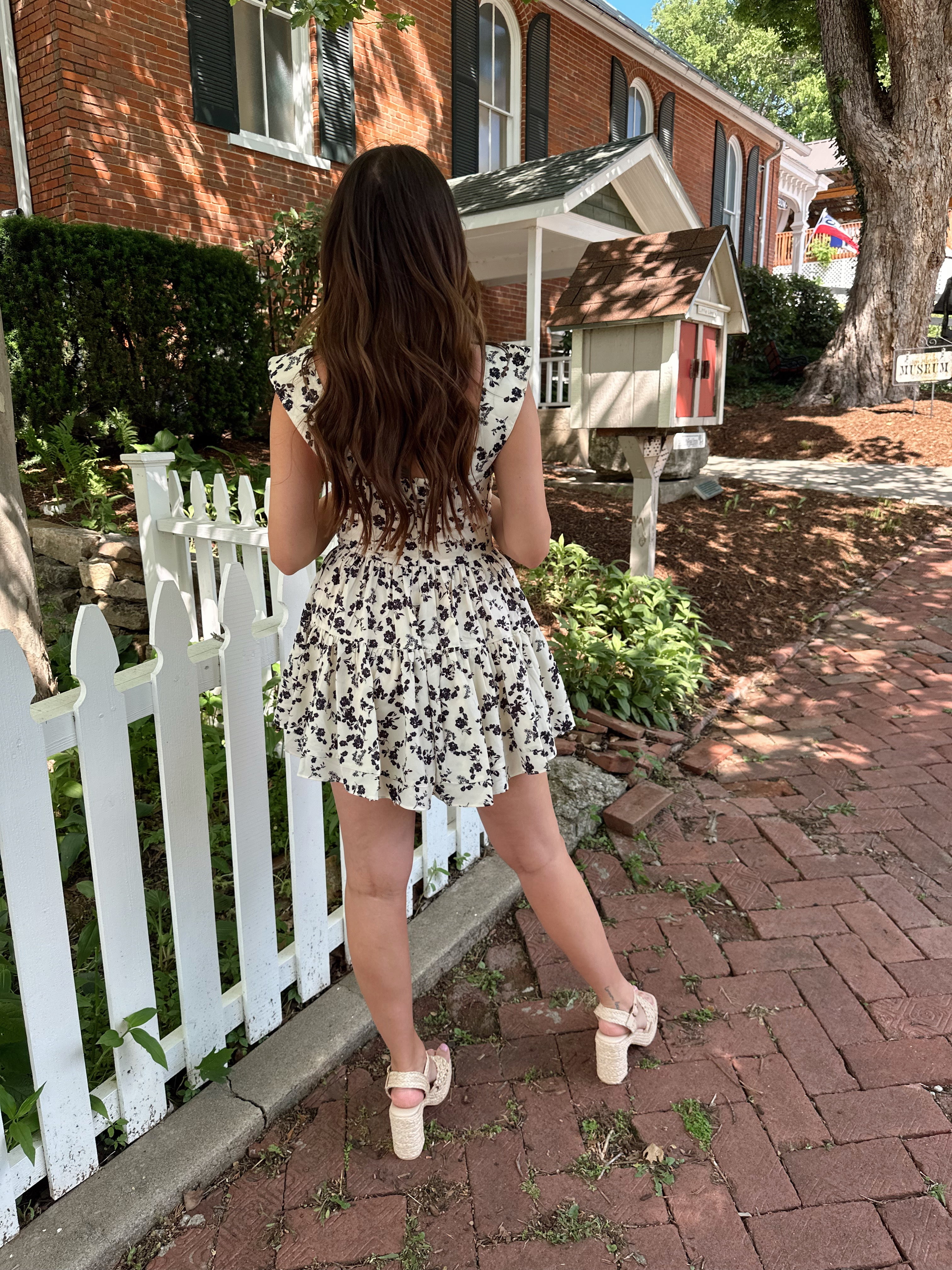 Ivory tiered romper with black floral pattern and button detailing.