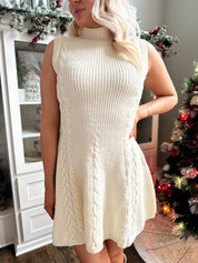 Woman wearing cream cable knit fit to flare sweater mini dress.