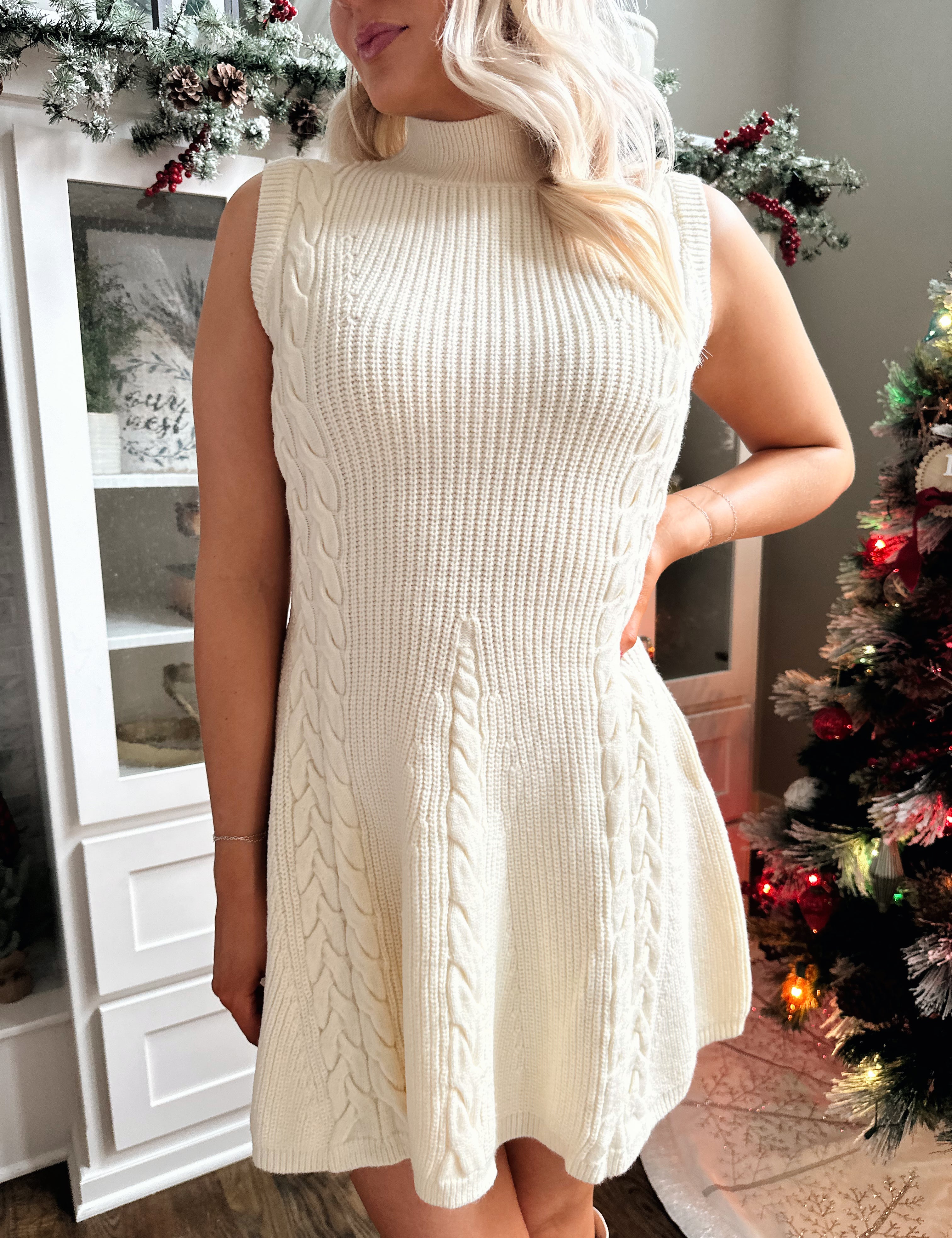 Woman wearing cream cable knit fit to flare sweater mini dress.